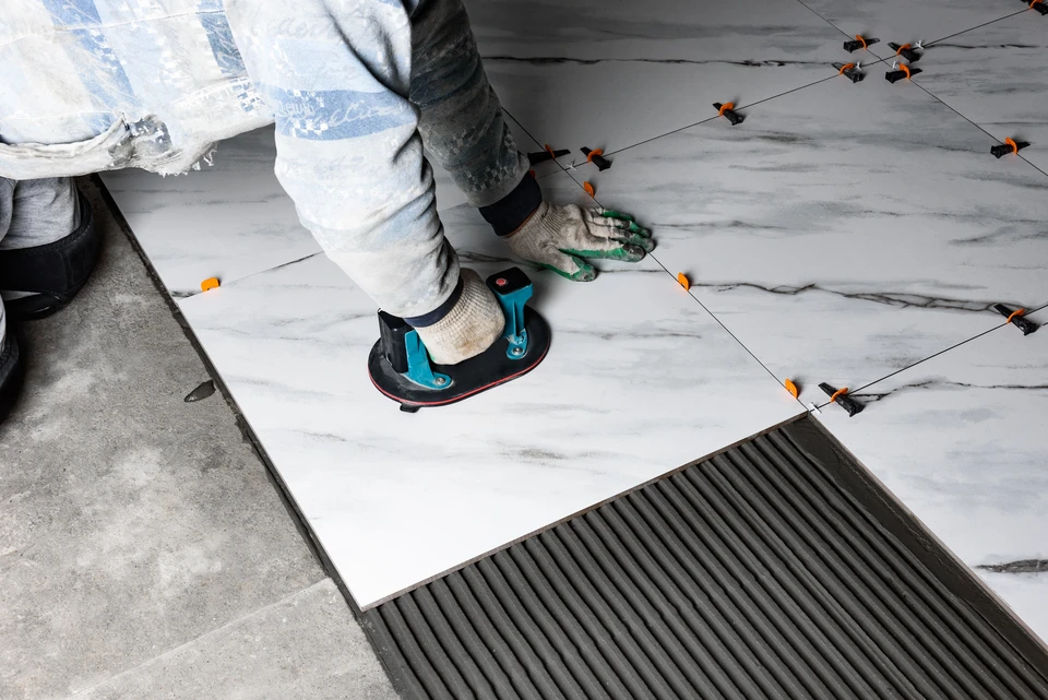 Ouvrier carreleur installant des carreaux de céramique bleus sur mur intérieur
